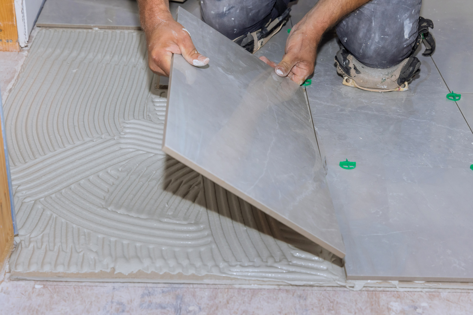 Using adhesive to install ceramic floor tiles in a home cons